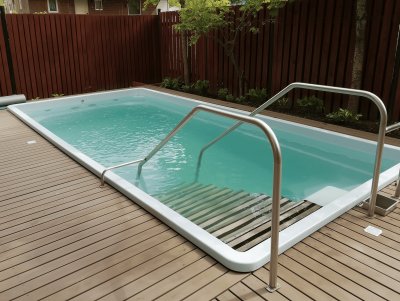 Прямоугольный бассейн с белой чашей и металлическими поручнями на деревянной террасе